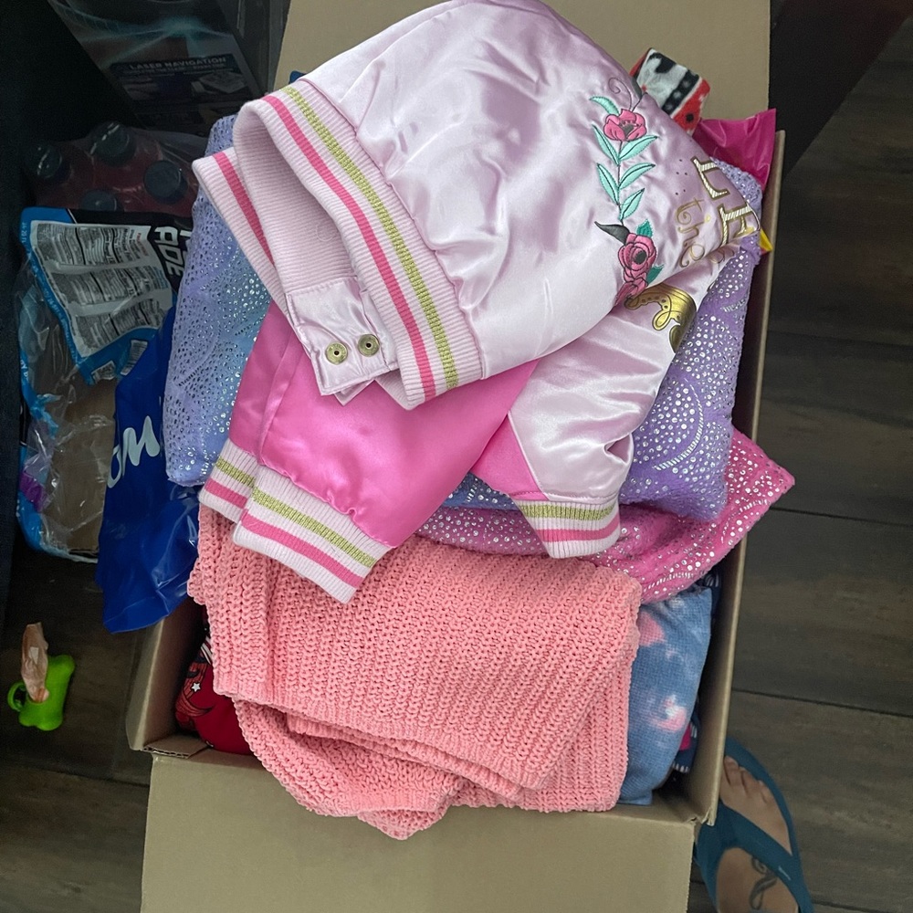 Some brand new girl clothes mixed in with old clothes.